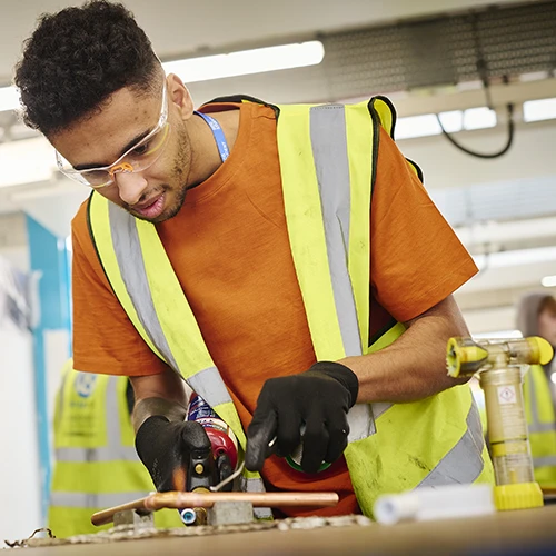 student soldering copper pipes