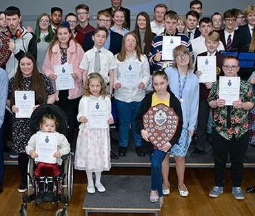 Young people of all ages in group holding certificates