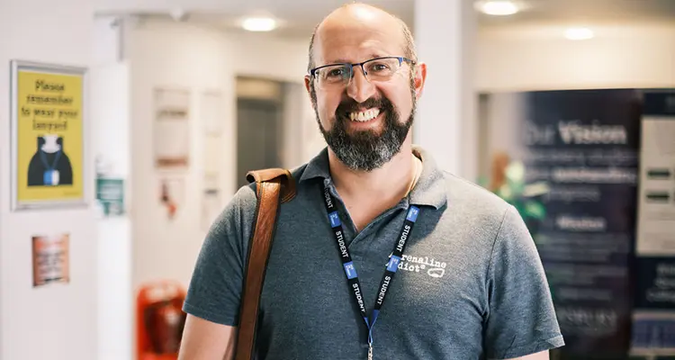 Mature male student smiling in corridor of college