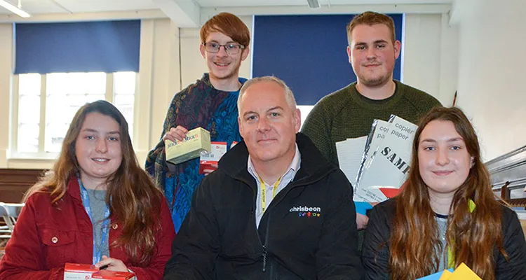 Four students with Managing Partner from Chrisbeon holding stationery that they will take to Ghana