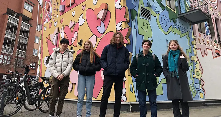 Students standing in front of graffitied building