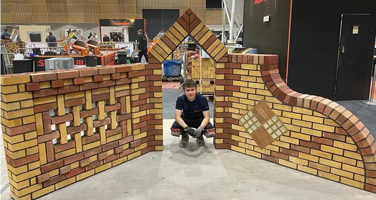 Student crouching down under brick arch