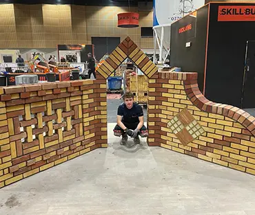 Student crouching down under brick arch