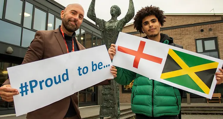 Student and staff member holding signs of what they are proud to be