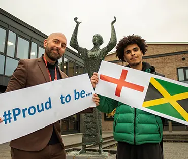 Student and staff member holding signs of what they are proud to be