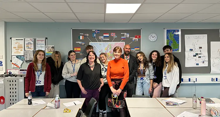 Group of students, staff and employers standing together smiling in classroom