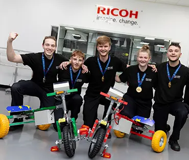 Small group of students smiling in front of made bikes