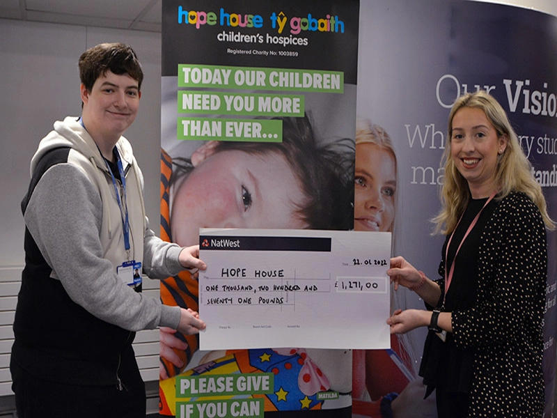 Student handing over a cheque to Hope House representative