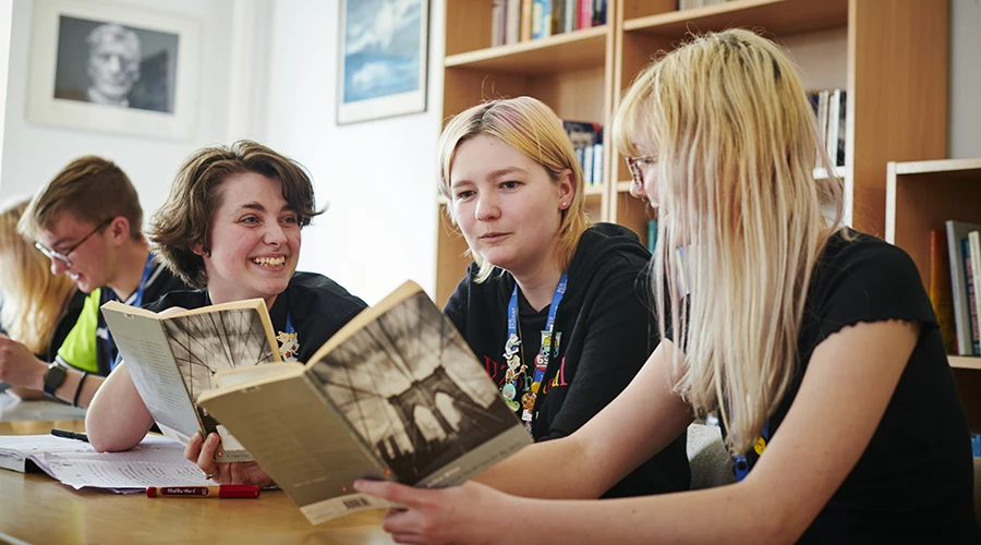 Students smiling and reading text books together 