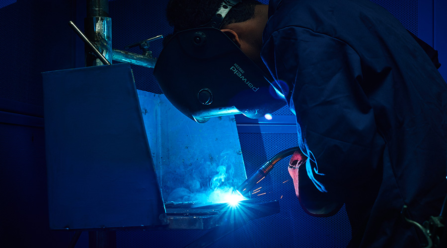 Student in welding mask and torch