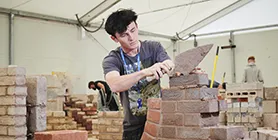 Student with trowel constructing archway