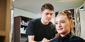 Student cutting person's hair