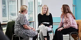 Three mature students talking in classroom