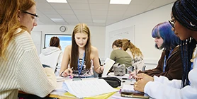 Students around table reading and writing 